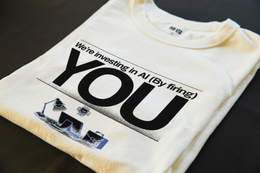 Folded T-Shirt mockup - We're Investing In AI (By Firing You) (CG5187) [dynamic_lifestyle]